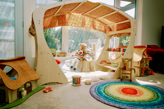 A wooden playstand with a canopy and various play areas set up inside, with toys and a child-friendly environment.