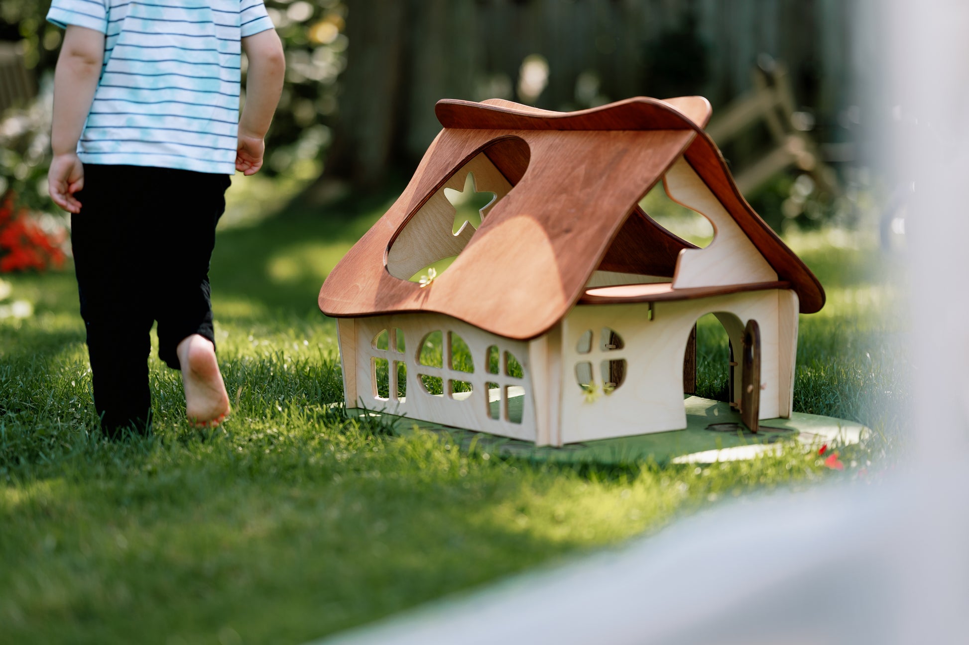 Child walking towards a small wooden house on grass